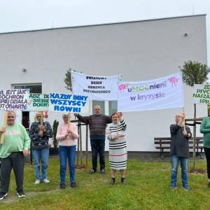 Grupa przed budynkiem trzyma banery: „uMocnieni w kryzysie”, „Zdrowie psychiczne – nasza wspólna sprawa”, „Bądź dla siebie dobry”, „Umysł jak spadochron…”.