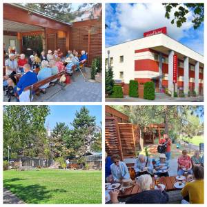 Widok na teren mini zoo w ogrodzie, drzewa i trawnik w EuroHotelu w Swarzędzu, seniorzy spacerują i odpoczywają.