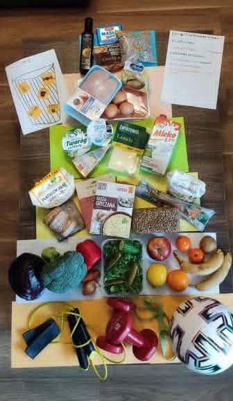 Produkty spożywcze, owoce, warzywa i artykuły pełnoziarniste ułożone na stole podczas warsztatów o piramidzie żywieniowej dla seniorów.