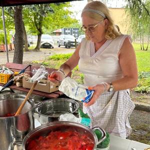 Prowadząca przygotowuje przetwory z pomidorów w dużych garnkach podczas warsztatów.